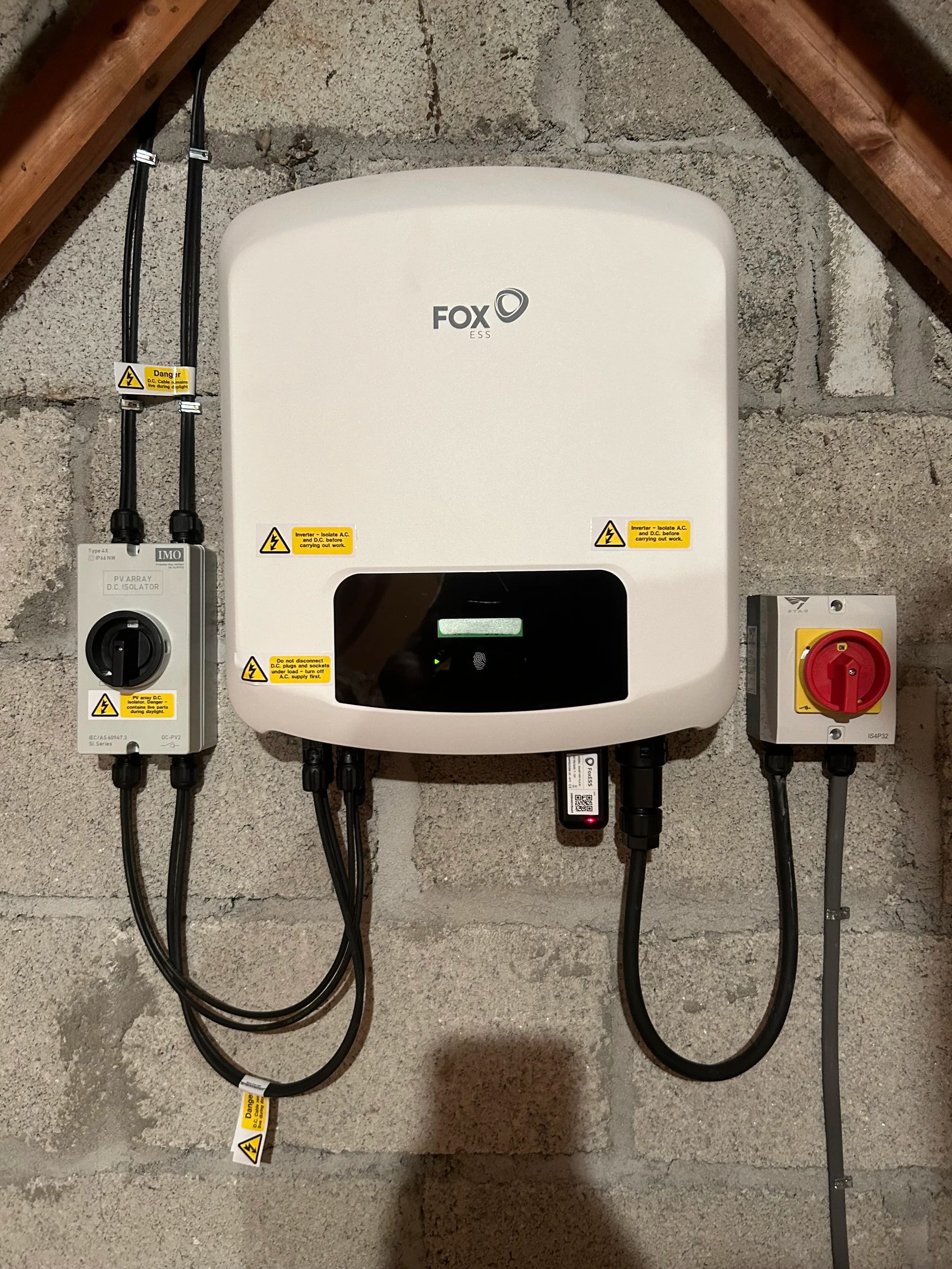 A FoxESS inverter with isolator switches mounted on the loft wall at Thanckes House