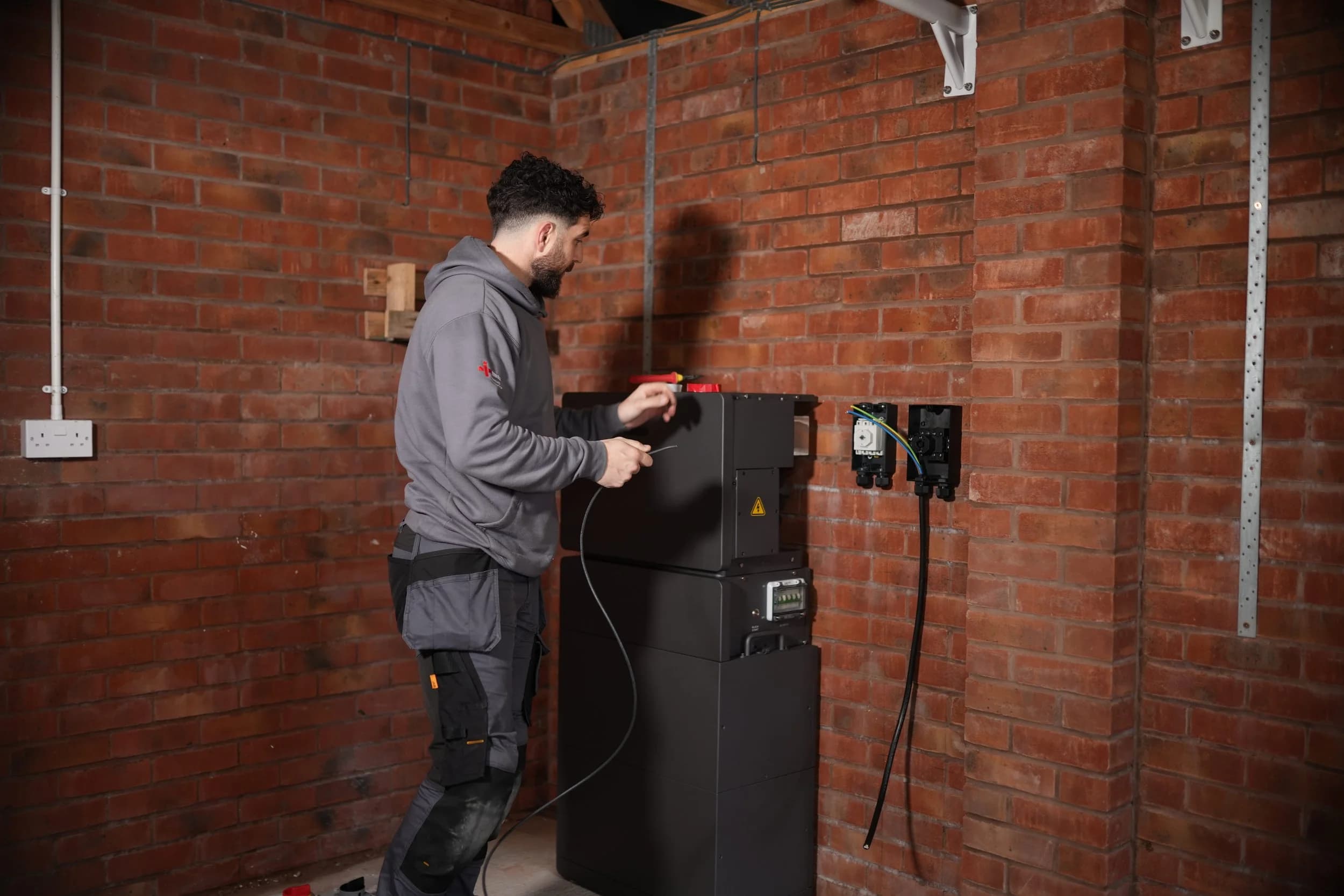 Simple Solar installer connecting a home battery backup system against a brick wall.