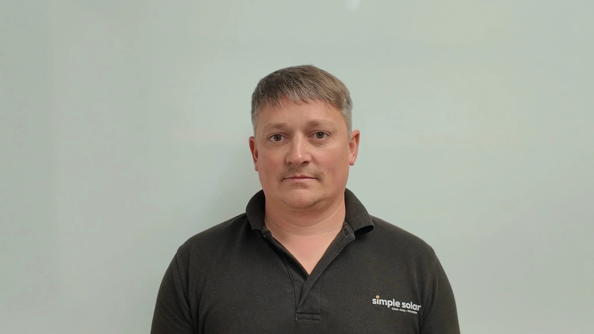 Headshot of Ben Quick wearing a Simple Solar black polo shirt.