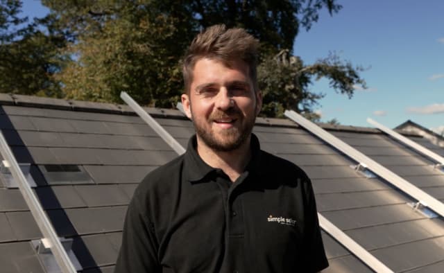Simple Solar team member standing beside a solar installation