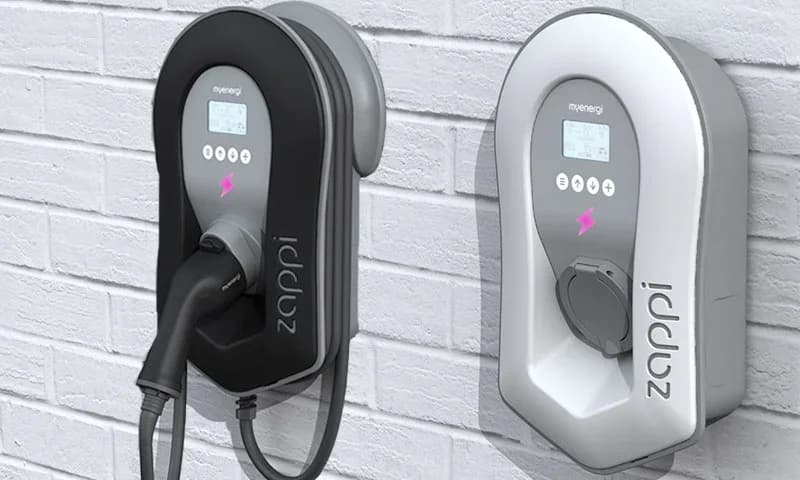 Two Zappi home EV chargers mounted on a brick wall, shown in black and white.