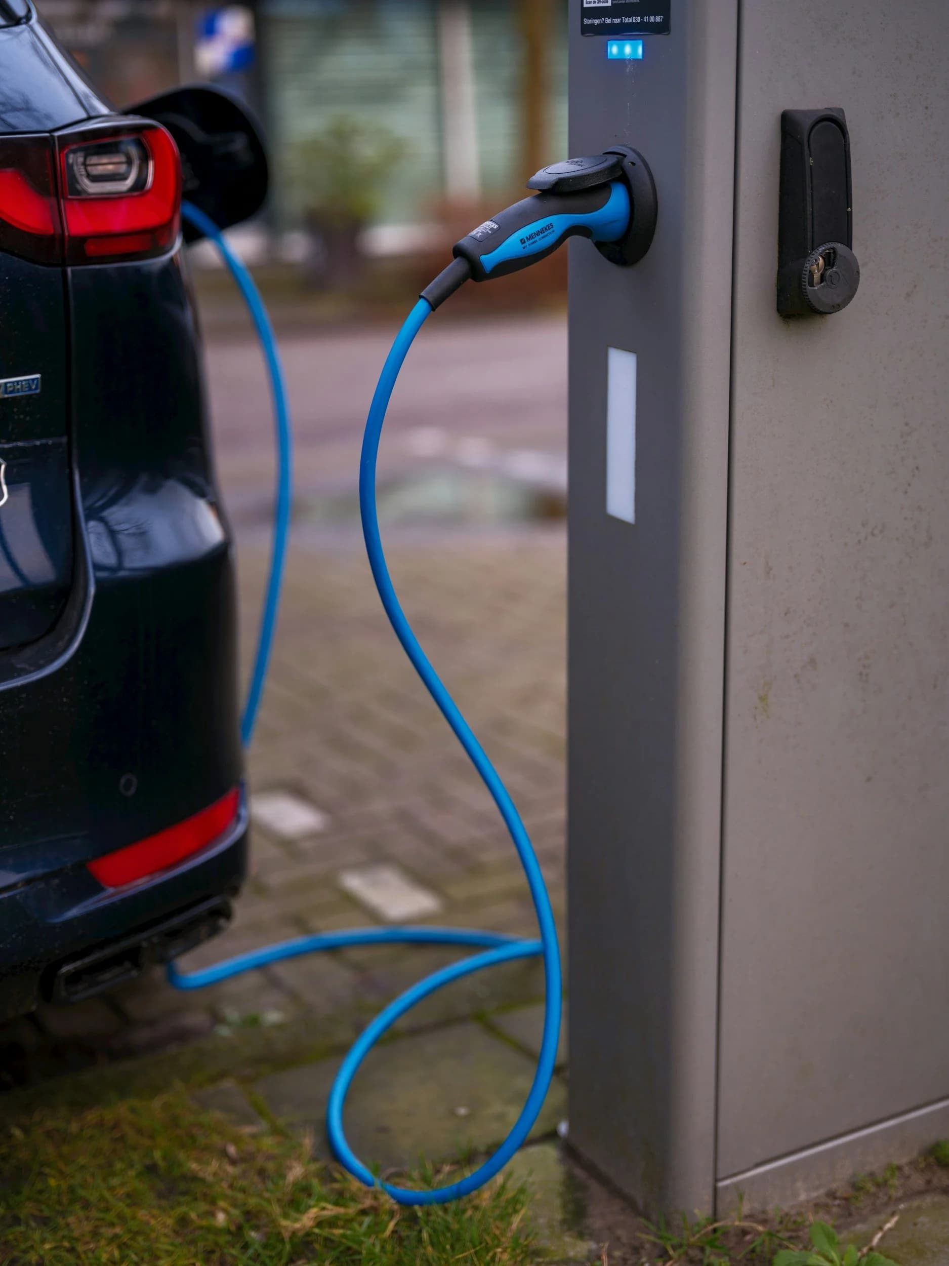 Electric car charging from a public charging point using a blue charging cable.