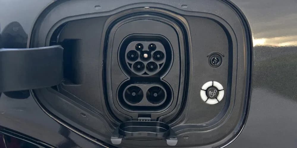 Close-up of an electric vehicle charging port with the connector socket and charge indicator light.